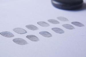 different black fingerprints on a paper close up , photo