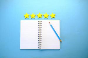 Customer review concept. Rating golden stars and notepad on blue background photo