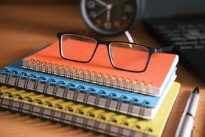 Bloc de notas, anteojos y un lápiz sobre la mesa de madera foto
