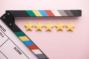 Rating golden stars and movie clapper board on color background photo
