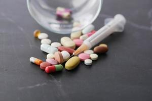 syringe and pills on dark background, close up photo