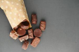 dark chocolate spilling from a packet on black background photo