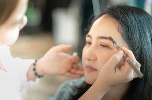 joven hermosa asiática se prepara maquillando por un maquillador profesional. foto