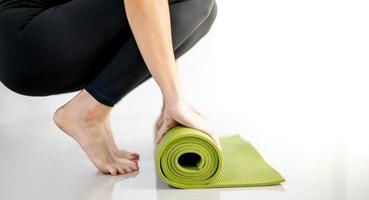 Female hand rolling green yoga mat for prepare exercise on the mat. photo