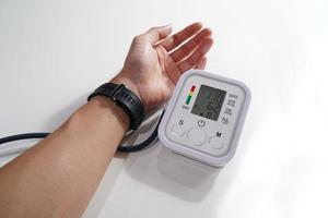 Monitoreo de la presión arterial de los pacientes que usan un monitor de presión arterial en la parte superior del brazo en la sala de examen de la clínica. En Tailandia foto