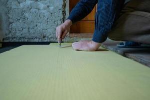 The master cuts expanded polystyrene on a floor, installation and warming of a floor in a room. photo