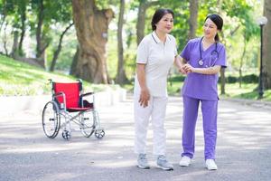 enfermera asiática cuidando a una paciente de mediana edad en el parque foto