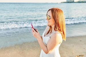 Red hair girl on the beach talking on the mobile photo