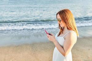 Red hair girl on the beach talking on the mobile photo