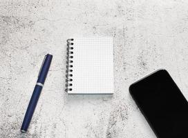 A notebook, pen and mobile phone in a work space photo