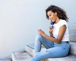 Hispanic female happily taking notes while sitting on the stairs photo