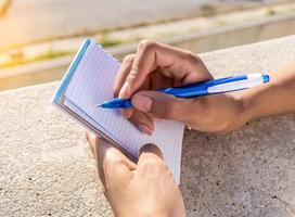 persona escribiendo sus nuevas ideas en un cuaderno foto