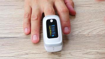 Man is monitoring his blood oxygen saturation using mobile oxymeter fingertip device - people with technology healthcare concept video