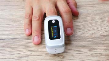 Man is monitoring his blood oxygen saturation using mobile oxymeter fingertip device - people with technology healthcare concept video