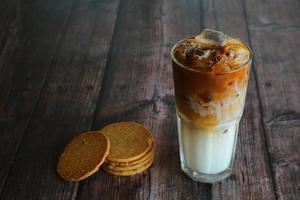 A glass of iced coffee with biscuits beside and have copy space. Iced latte with cookies on wooden table. photo