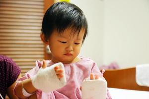 el bebé asiático tiene fiebre y luego fue ingresado en el hospital y recibió un tubo intravenoso con una almohadilla en las manos para proteger la aguja del medicamento. foto
