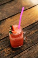 Glass of strawberry smoothie and fresh strawberries on top and have wooden background. Healthy food and drink concept. photo