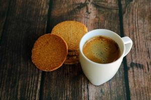 A cup of hot espresso with biscuits on wooden table. Hot coffee with cookies. photo