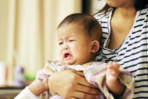 Asian baby crying in hospital with mother. Sick child with mother in hospital photo