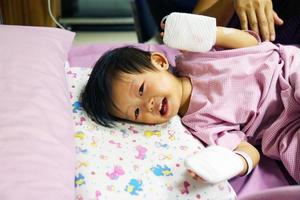 el bebé asiático tiene fiebre y luego fue ingresado en el hospital y recibió un tubo intravenoso con una almohadilla en las manos para proteger la aguja del medicamento. foto