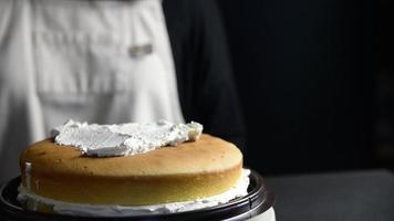 dame a mis de la crème sur le gâteau à l'aide d'une spatule - personnes avec un concept de boulangerie maison video