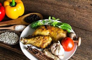 Roasted chicken with ingredients on wooden table. photo