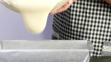 Chef pouring butter cake cream into mold container before putting to the oven - people preparing homemade bakery concept video