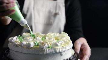 chef signora che fa le rose dalla crema per la decorazione di torte mentre prepara la vista dall'alto del forno fatto in casa su sfondo nero video