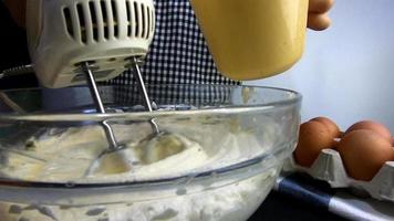 Lady is making homemade cream cake using electric portable mixer machine video