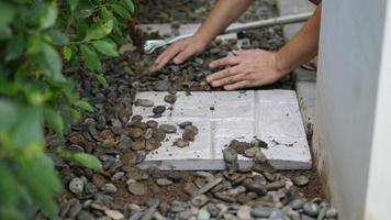 le jardinier travaille avec la décoration du sol du jardin à la maison en utilisant une dalle de béton et un matériau en pierre