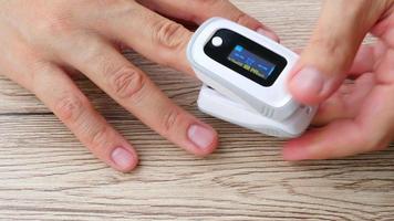 Der Mensch überwacht seine Blutsauerstoffsättigung mit einem mobilen Oxymeter-Fingerspitzengerät - Menschen mit Technologie-Gesundheitskonzept video