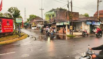 Sukoharjo - May 16, 2022 - motorcyclists pass through the wet asphalt road at the intersection photo