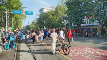 sukoharjo - 16 de mayo de 2022 - el anciano conduce su bicicleta en una multitud de personas que caminan durante un evento en solitario del día sin automóviles foto