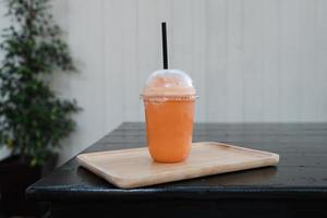 Thai milk tea frappe in takeaway cup on wooden table photo