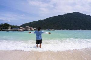 man in the back with arms out standing on wavy beach photo