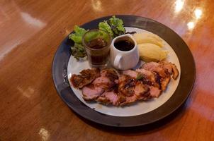 sliced duck steak with sweet and sour sauce on wooden dinner table photo