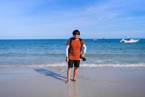 happy middle age Asian  backpack photographer tourist man standing on beach and smile photo