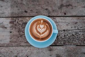 top view of a cup of hot coffee latte on wooden table photo