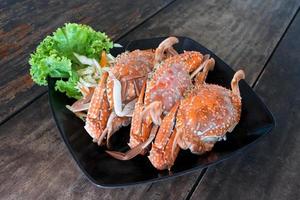 steamed blue swimming crabs on black dish on wooden table photo