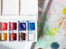 box of watercolors on a paint-stained palette photo