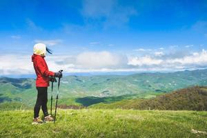 Caucasian woman stand on panoramic Ikvlivi mount viewpoint outdoors in spring nature. Nordic walk sticks usage outdoors photo