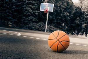 Basketball ball on asphalt against the background of the basket photo