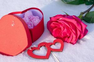 Romantic composition with a rose, a box of chocolates and a love message on the snow photo