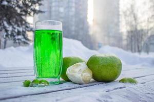 Fresh fruit juice in a glass and citrus fruits stand outdoors on a winter morning photo