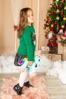 Beautiful little girl in green sweater in front of christmas tree photo