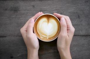 woman hands holding Latte art, coffee cup photo