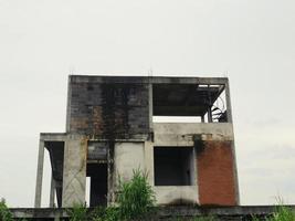 The unfinished house has a bit of grass, overlooking the sky. photo