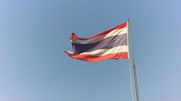 Slow motion of Thailand flag pole moving in blowing wind over bright blue sunny sky - nation flag freedom concept video