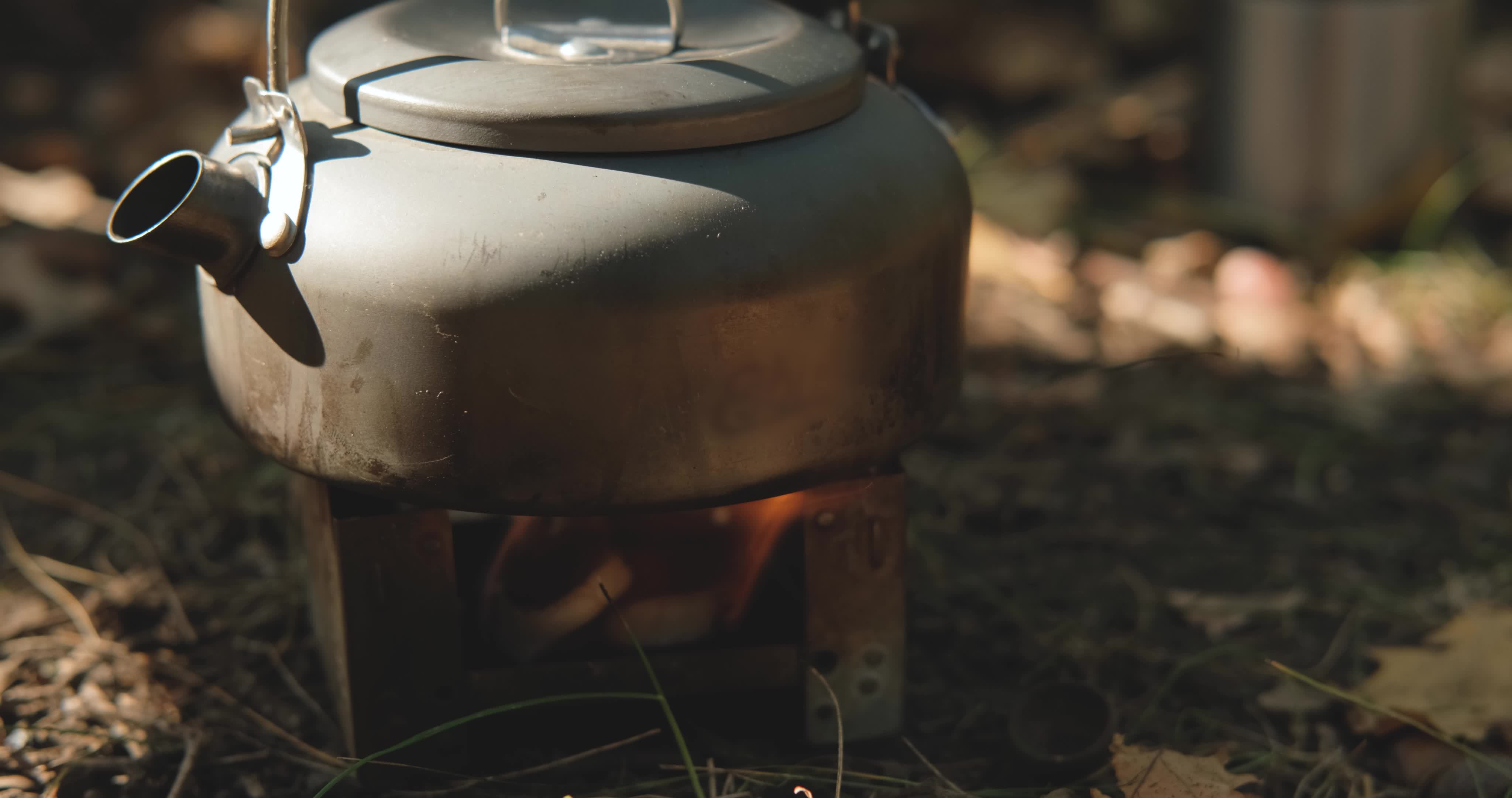 Close up of solid fuel stove with water kettle on fire, tea or coffee