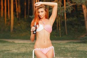 Beautiful girl with red hair holding a bottle of drink photo